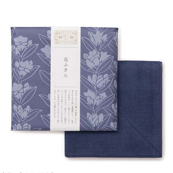 Dark blue tea towel packed in floral design wrapping paper on a white background