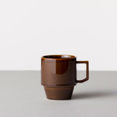 Brown ceramic mug on a light gray surface with a white background