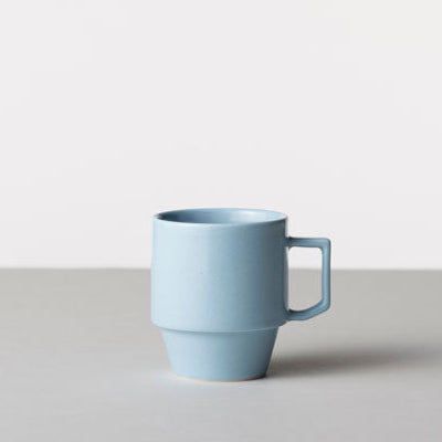 Blue mug on a light gray surface with a white background