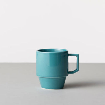 Turquoise mug on a light gray surface with a white background