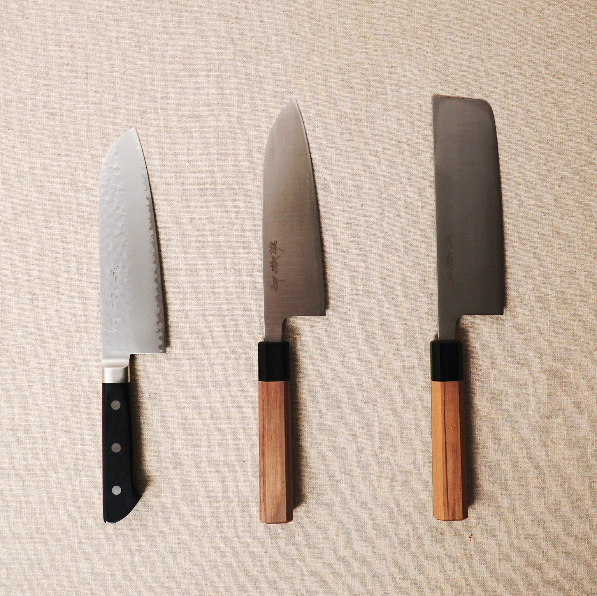 Three knives with wooden handles on a beige textured background