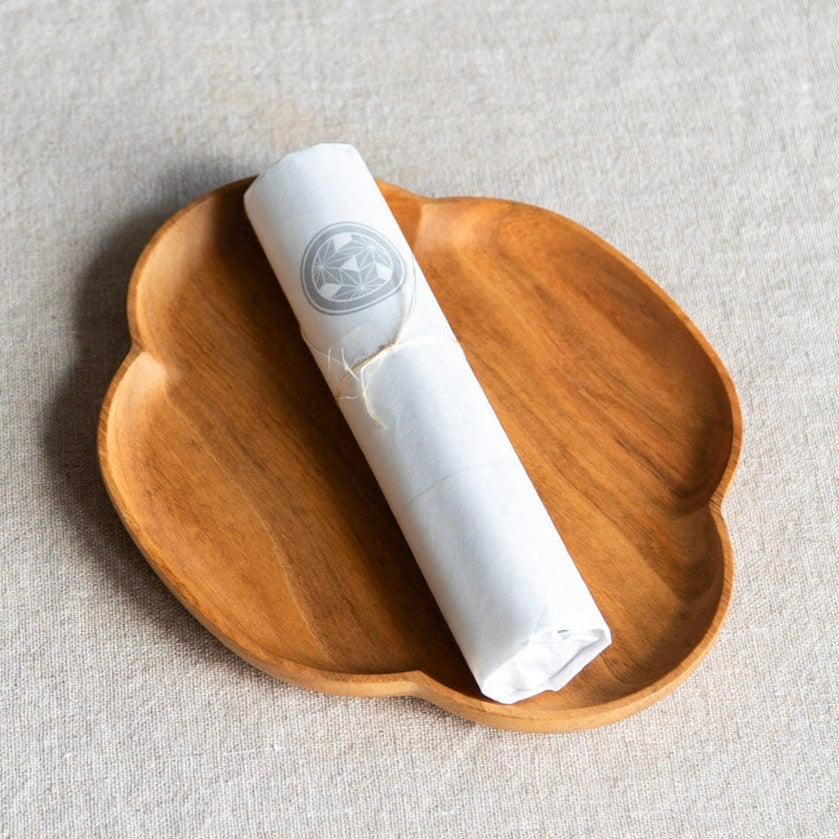 White roll of incense sticks on a wooden coaster with a light gray background