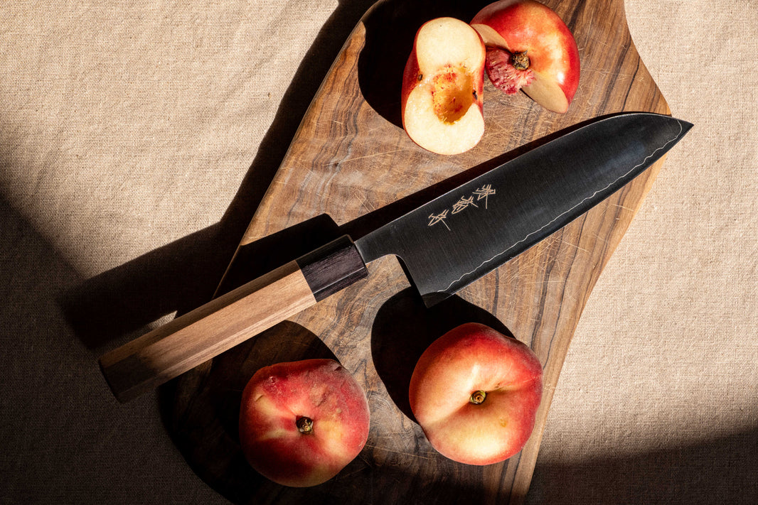 A Sakai Kikumori nakiri knife on a wooden worktop, blade angled to catch the light