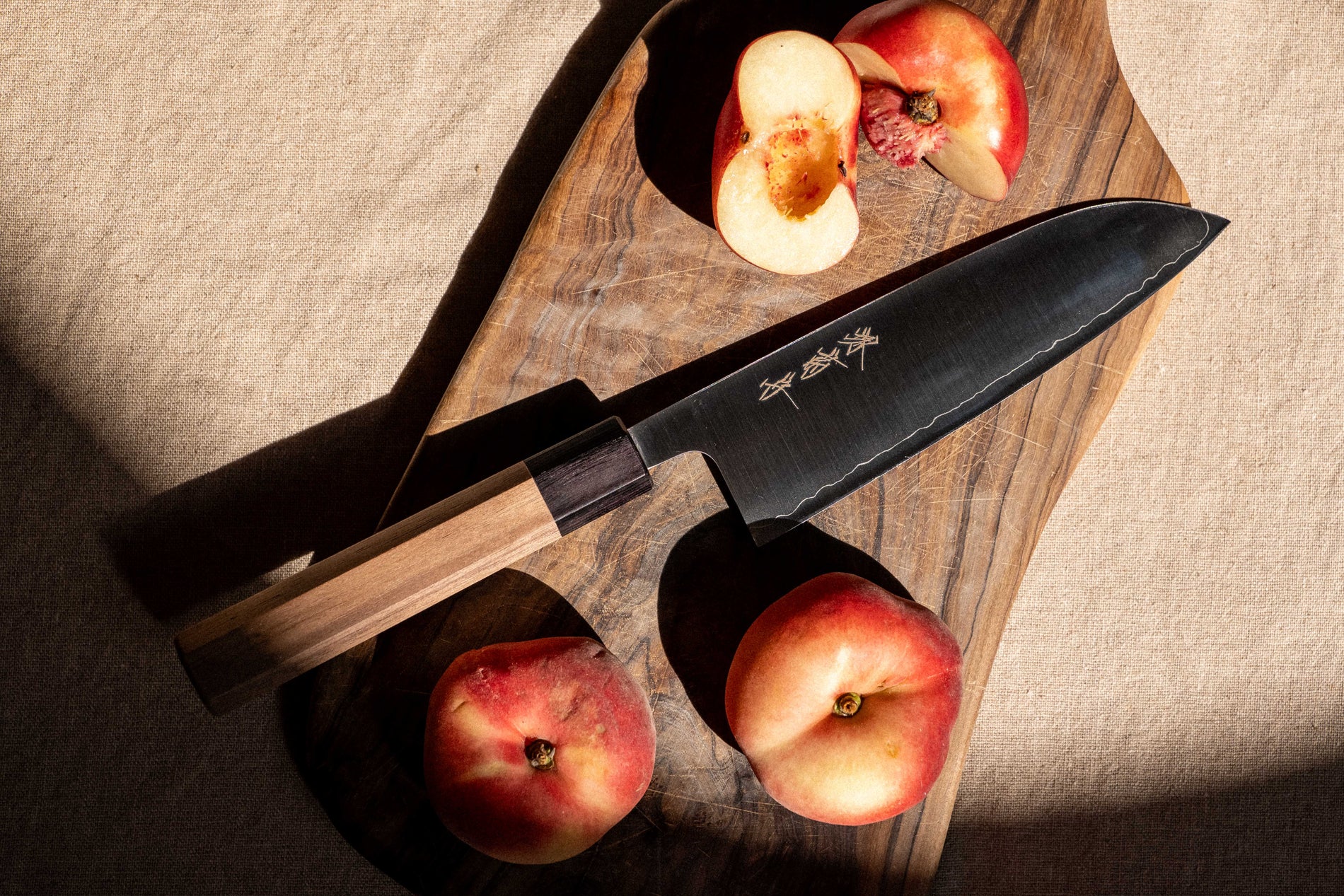 A Sakai Kikumori nakiri knife on a wooden worktop, blade angled to catch the light