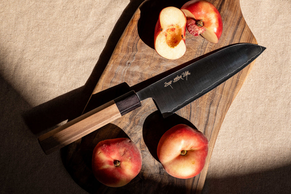 A Sakai Kikumori nakiri knife on a wooden worktop, blade angled to catch the light