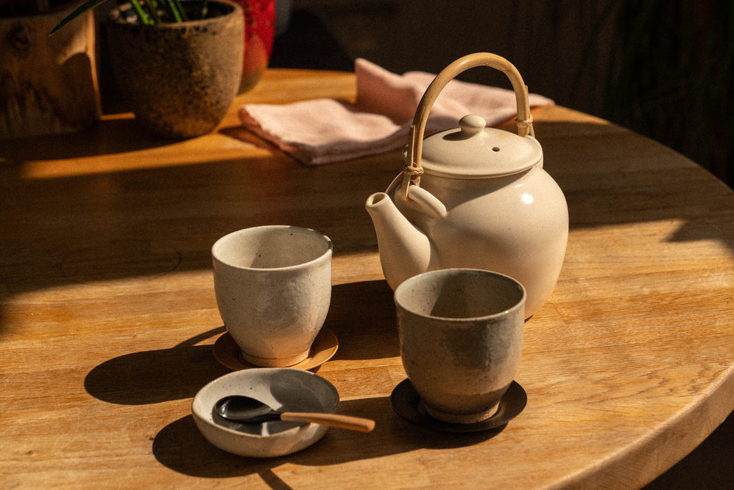 A Japanese tea setup on a wooden table — teapot, two cups