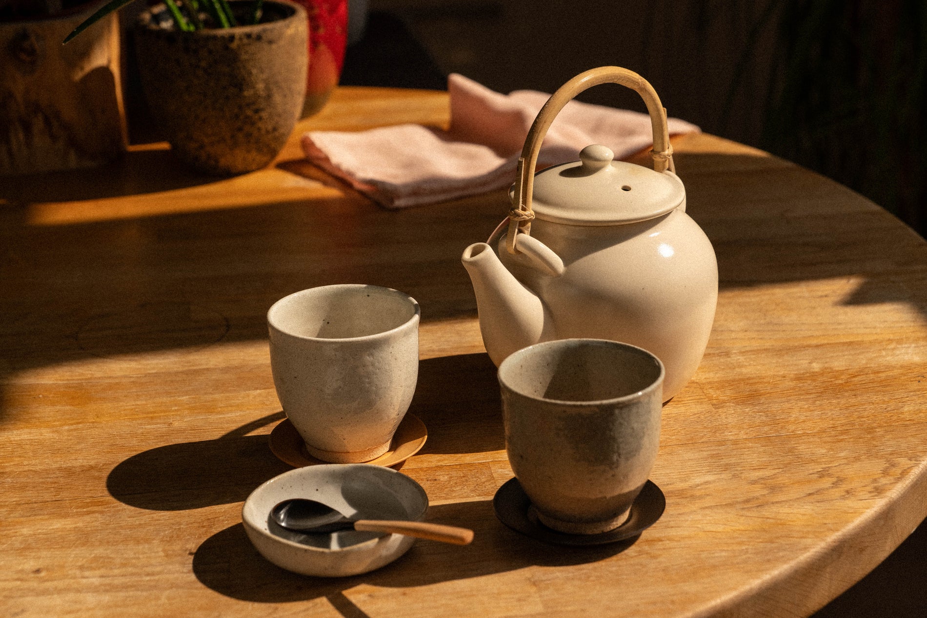 A Japanese tea setup on a wooden table — teapot, two cups