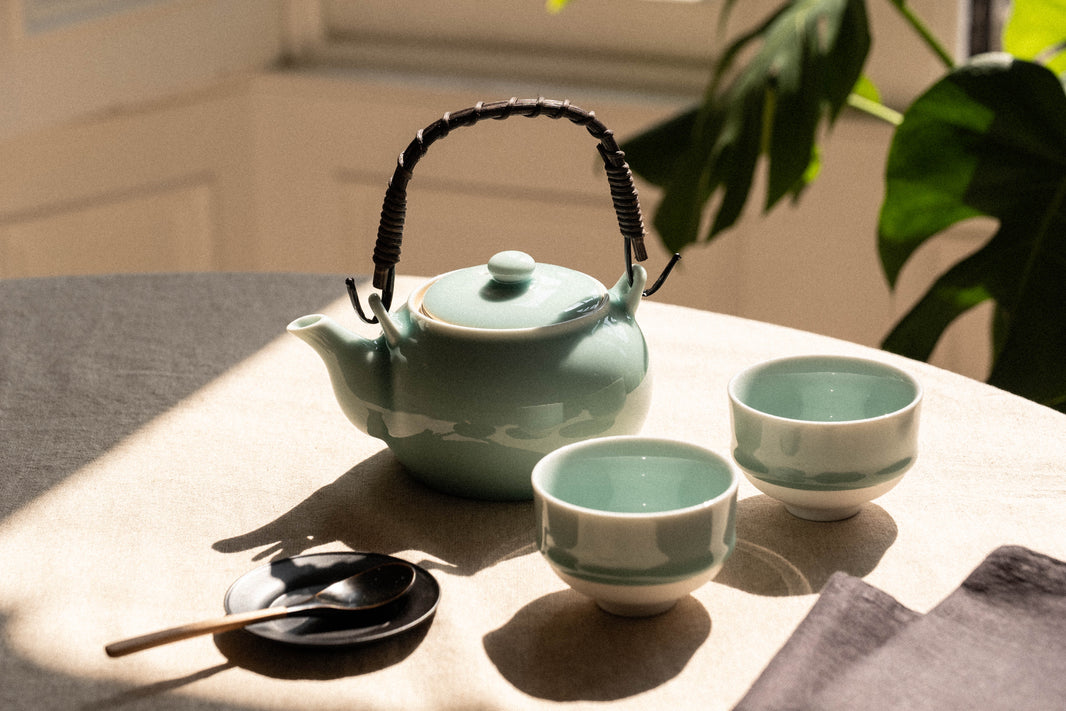Nabeshima Kosen Kiln celadon teapot and matching cups in jade glaze, on a linen-covered surface