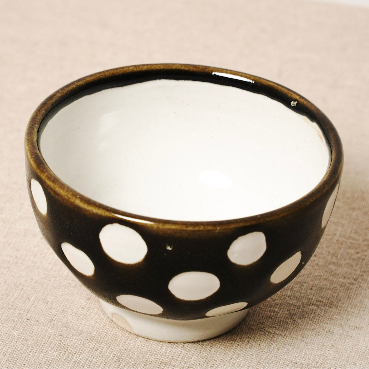 Ceramic bowl with white polka dots on a beige surface