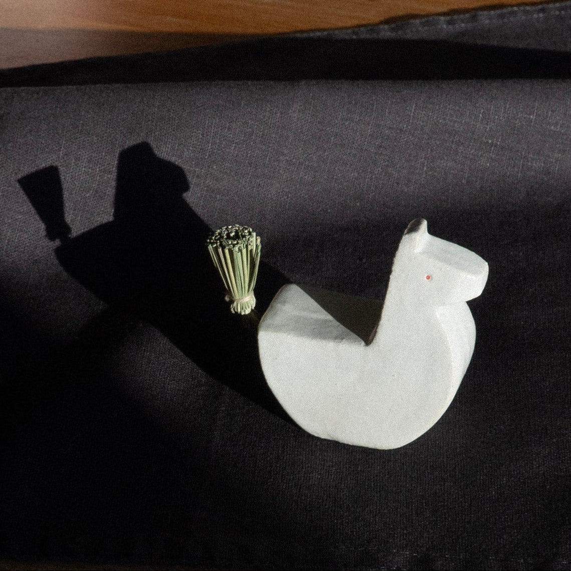 Decorative items including a white horse figure and gold ornament on a dark fabric surface.