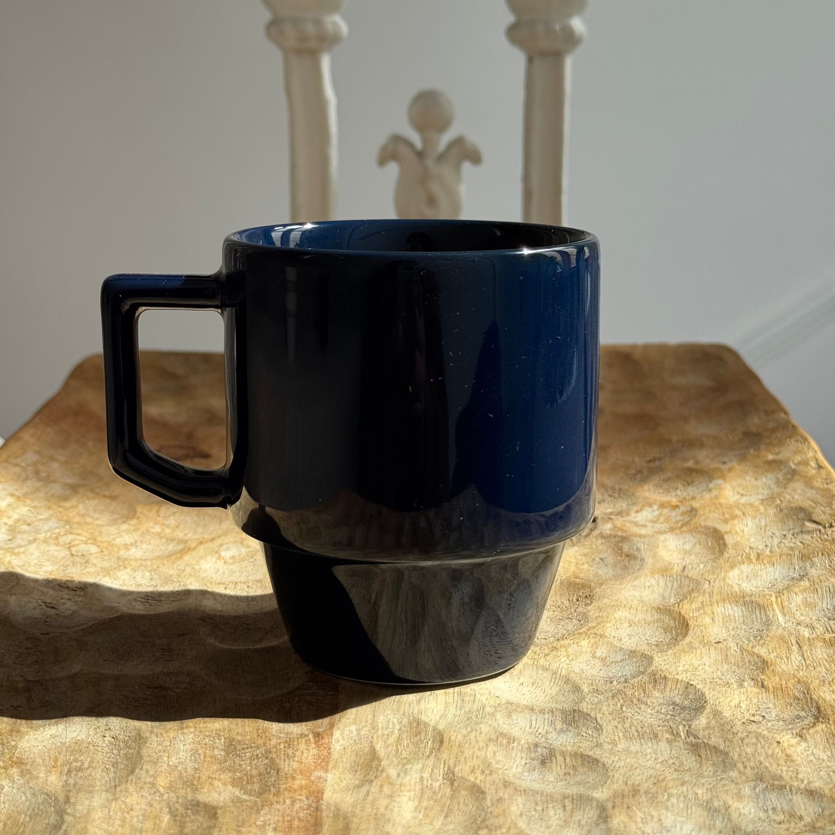 Blue mug with black handle on a textured surface