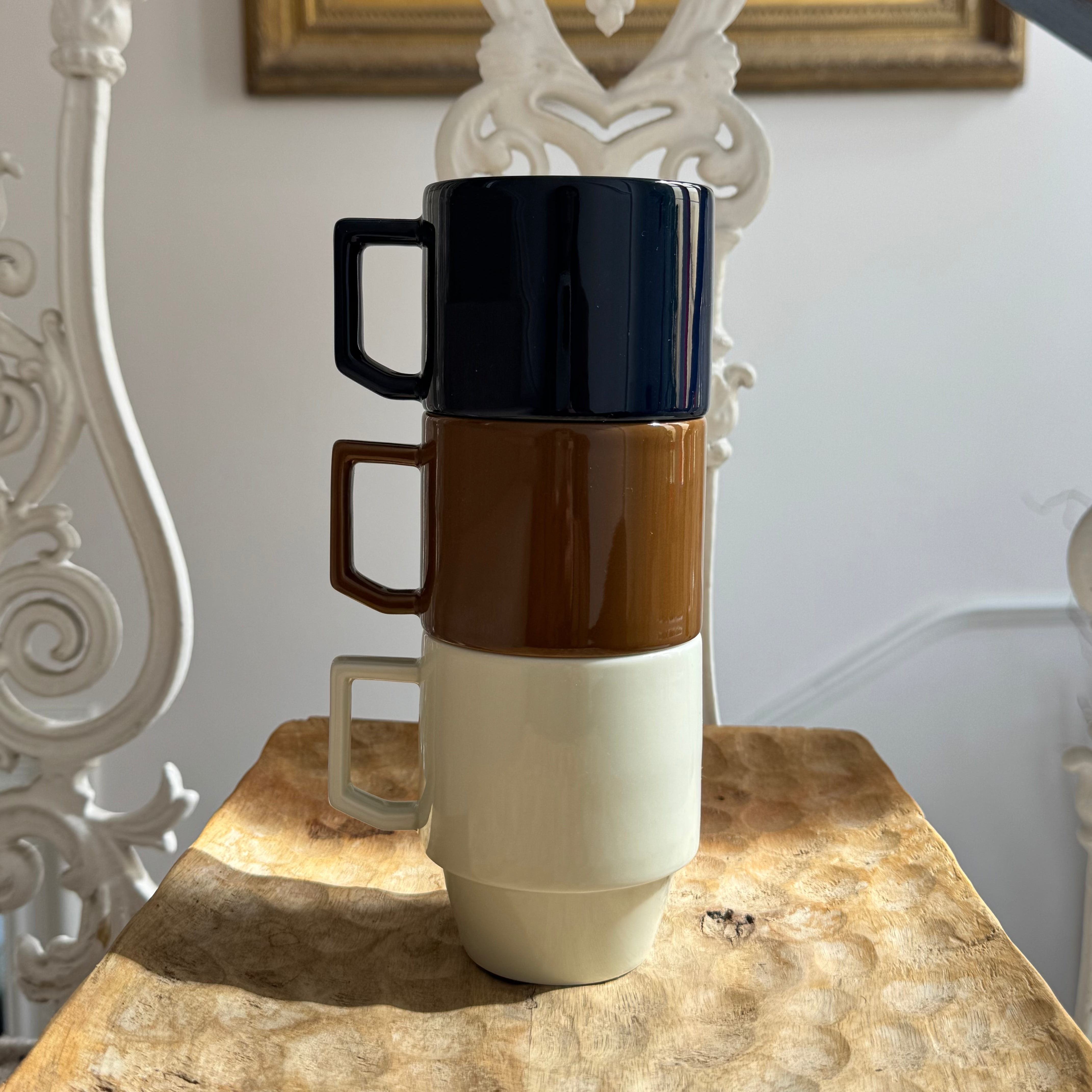 Stack of three ceramic mugs with different color layers on a marble surface.