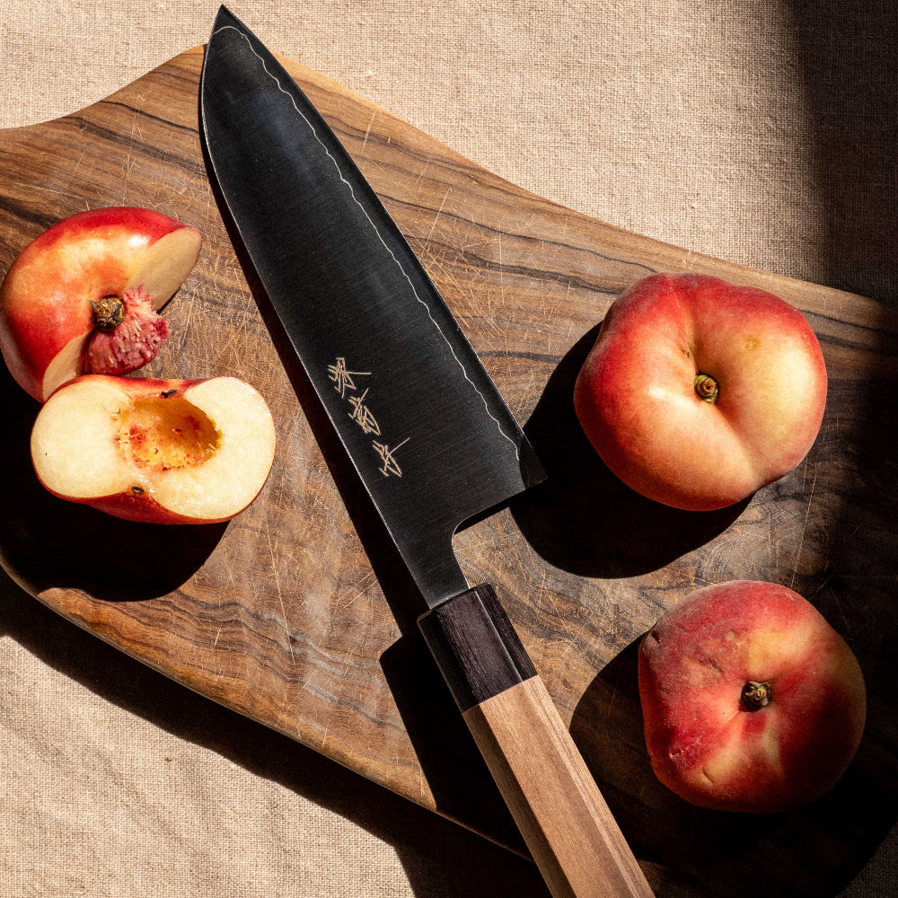 Knife on a wooden cutting board with peaches