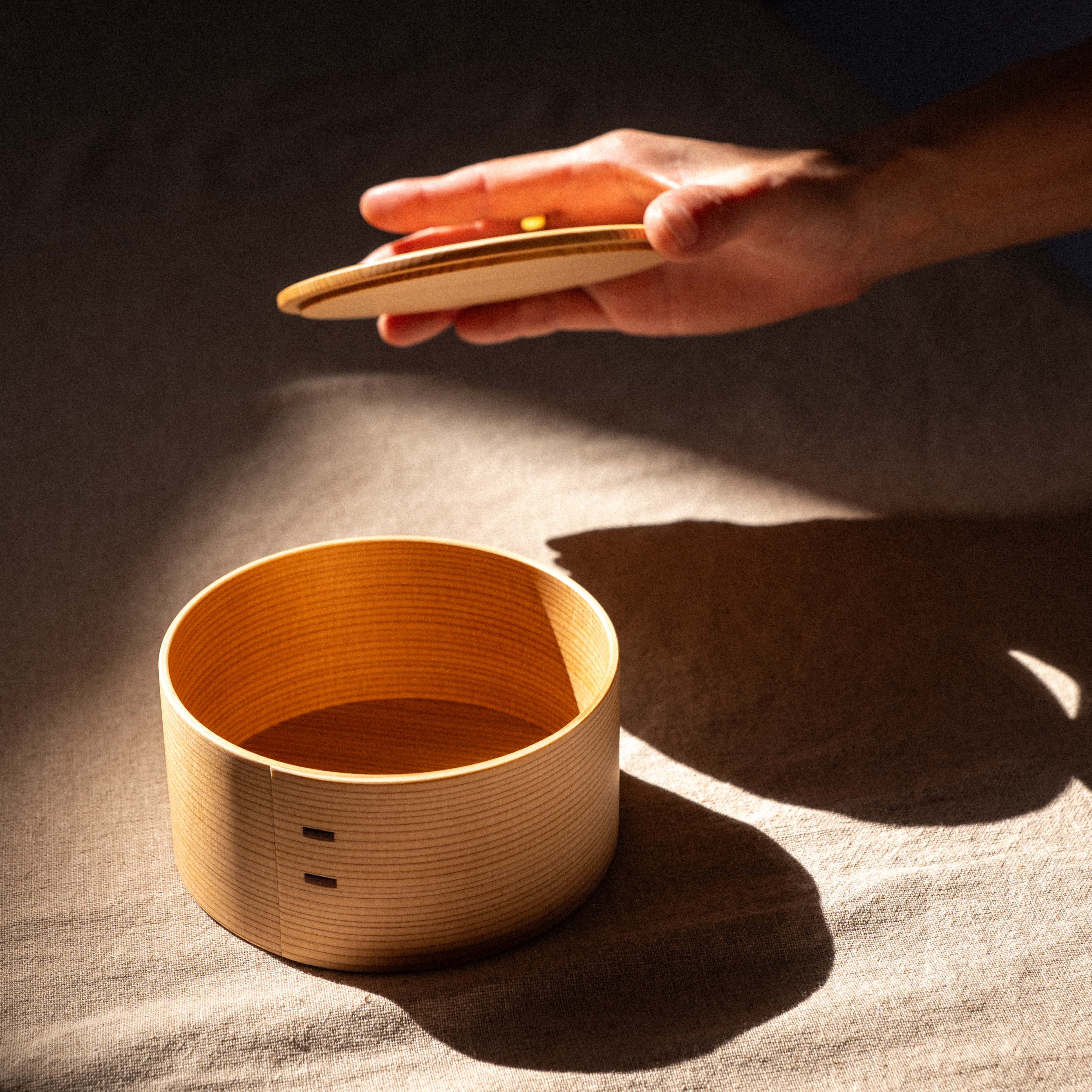 Person holding a set of wooden hand drums on a textured surface