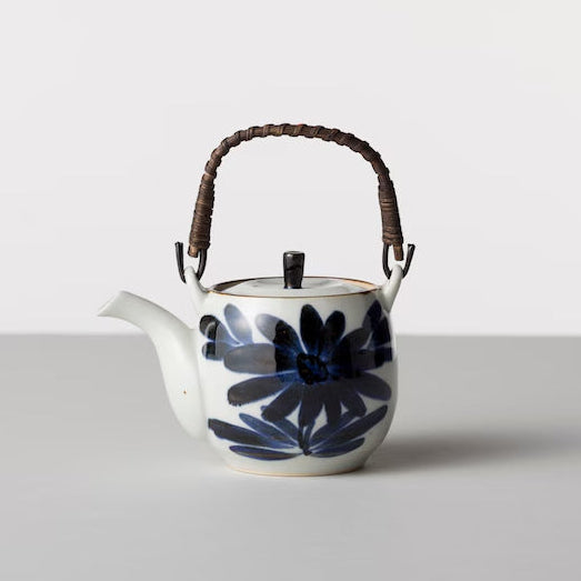 Ceramic teapot with floral design and wooden handle on a white background