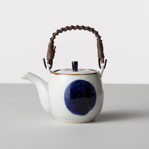White teapot with a blue circular design and brown handle on a light gray background