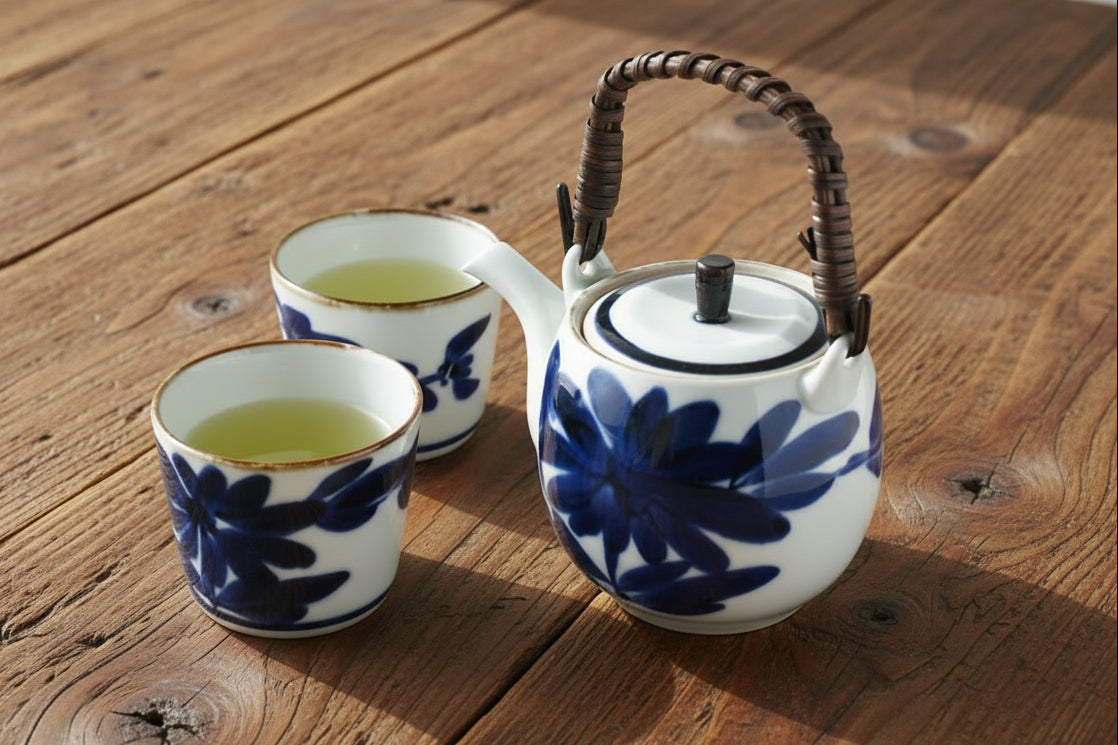Ceramic teapot and cups with floral design on a wooden surface