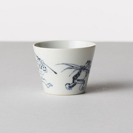 White ceramic cup with blue floral design on a light gray background