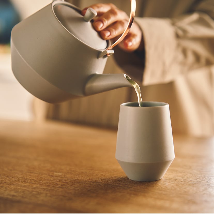 Person  pouring tea from gray Frustum teapot.