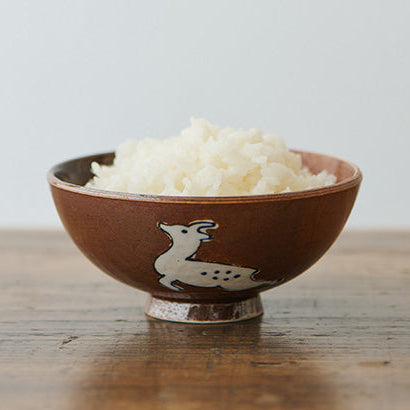 Ceramic bowl with rice on a wooden surface