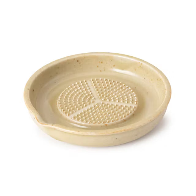 Beige ceramic dish with a textured center on a white background