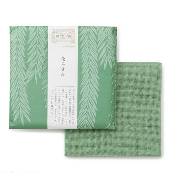 Green tea towel packed  in floral design  wrapping paper on a white background 