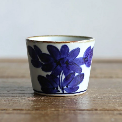 Ceramic cup with blue floral design on a wooden surface