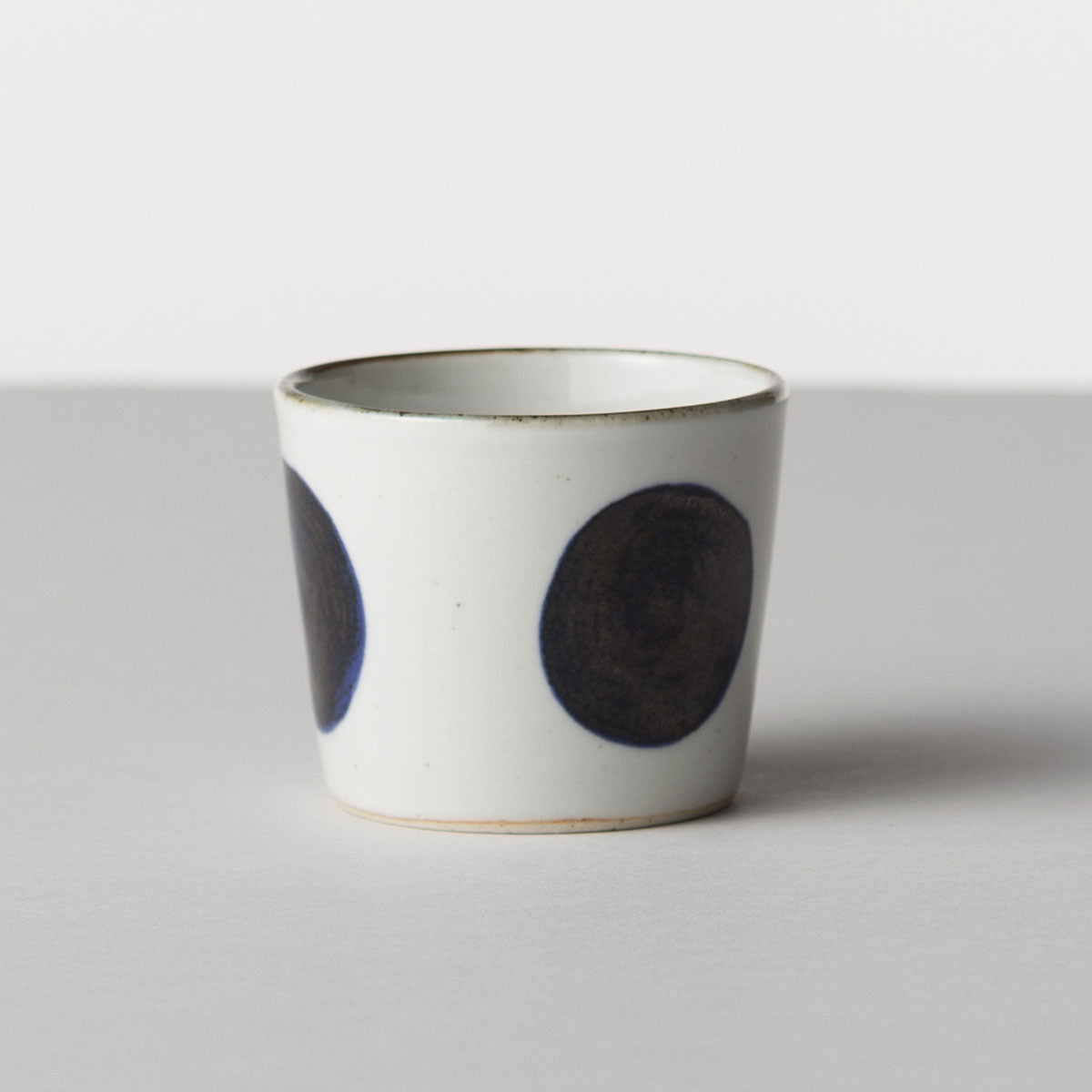 Ceramic cup with black circular patterns on a white background