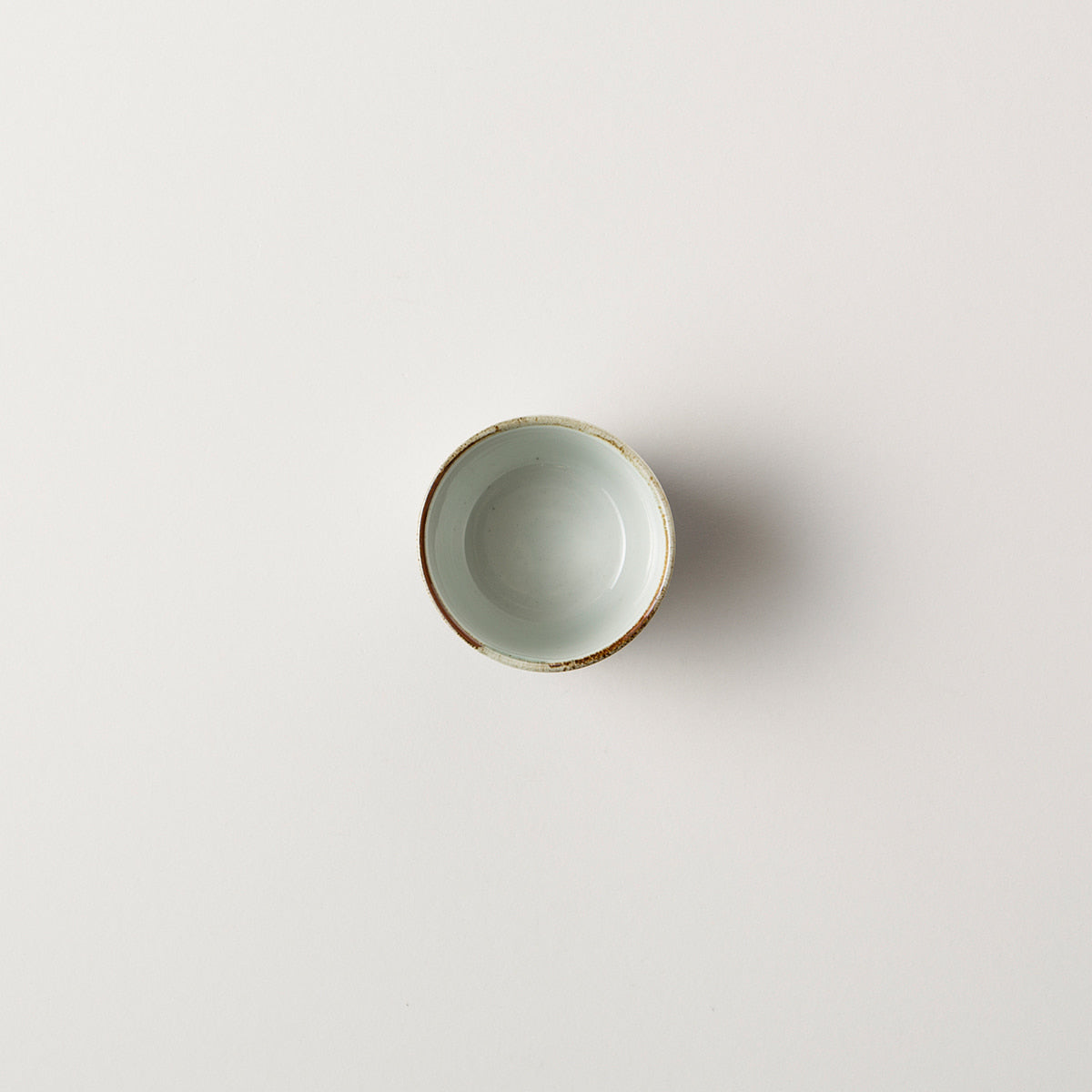 Small ceramic bowl with gold rim on a light gray background