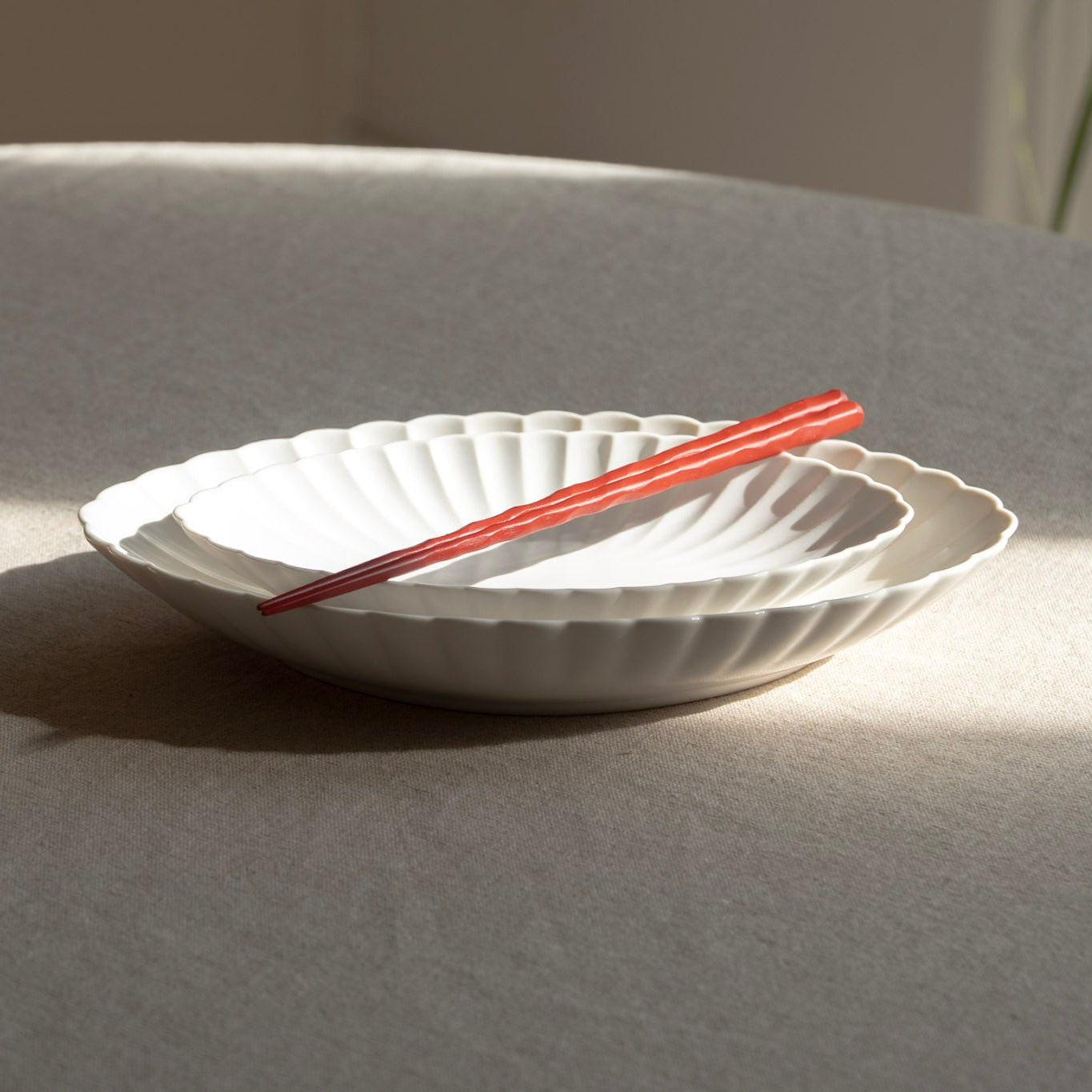White ceramic plate with red chopsticks on a light gray surface