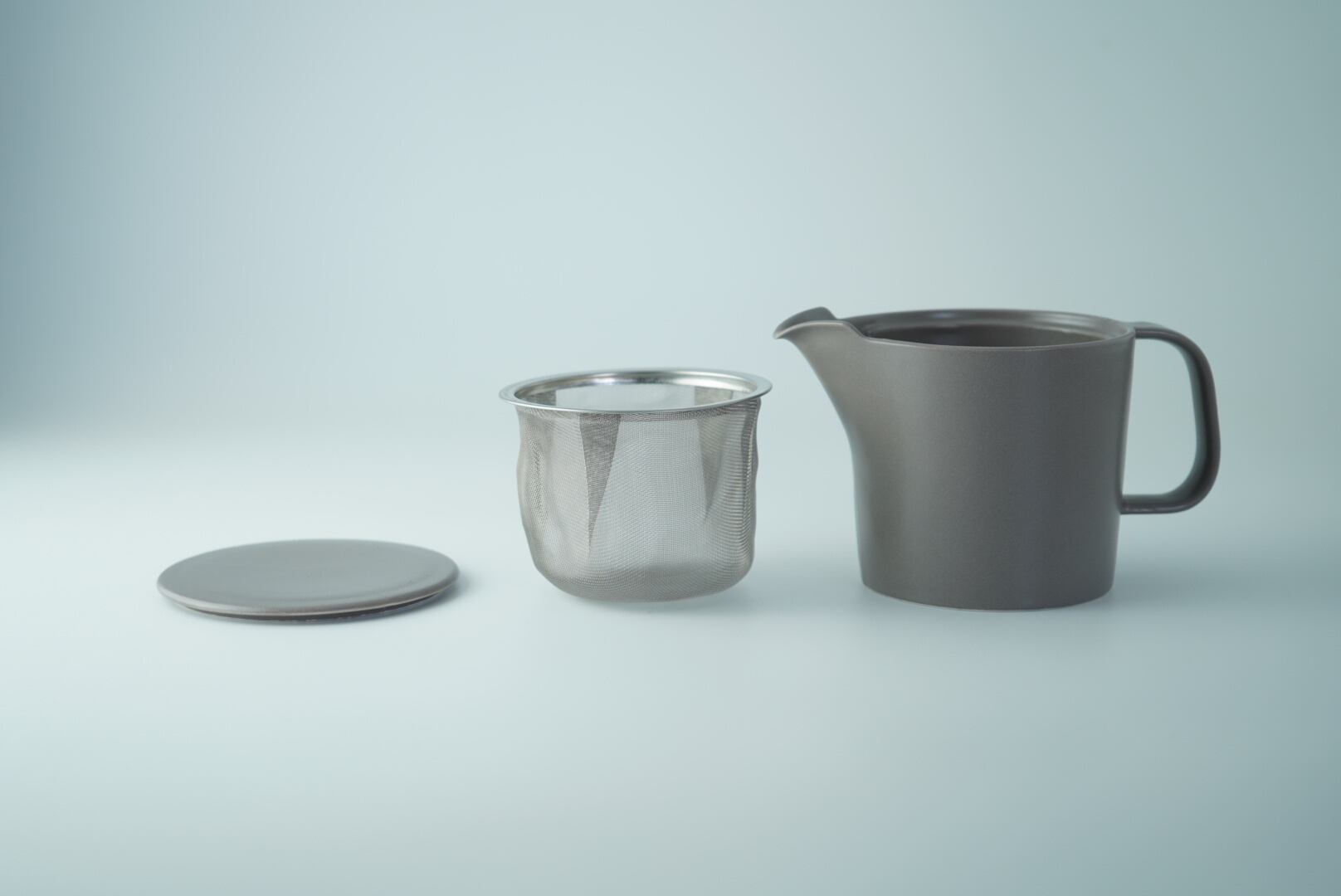 Gray teapot with a metal filter on a light gray background
