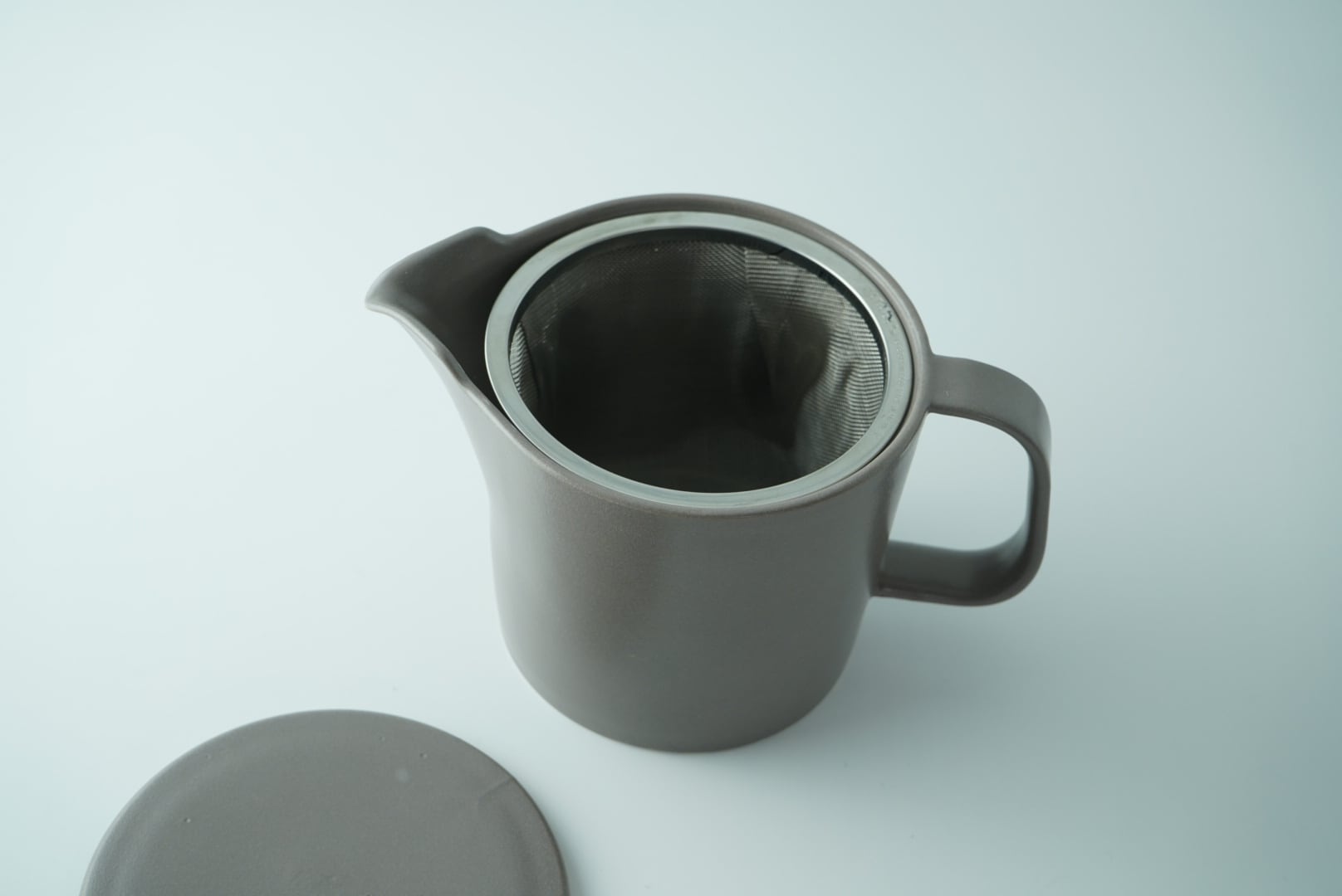 Gray ceramic teapot with lid on a light gray background