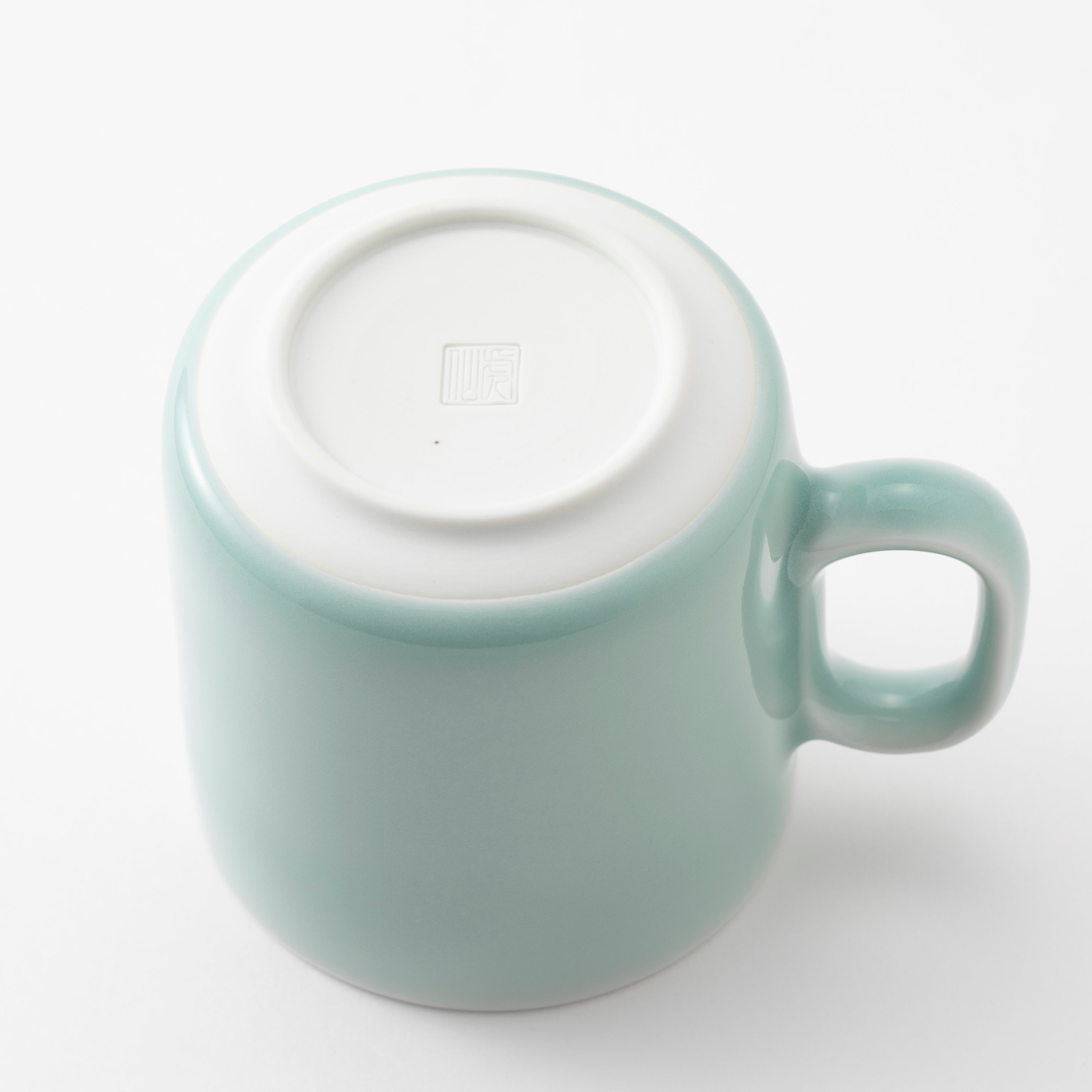 Light blue ceramic mug with a white lid on a white background