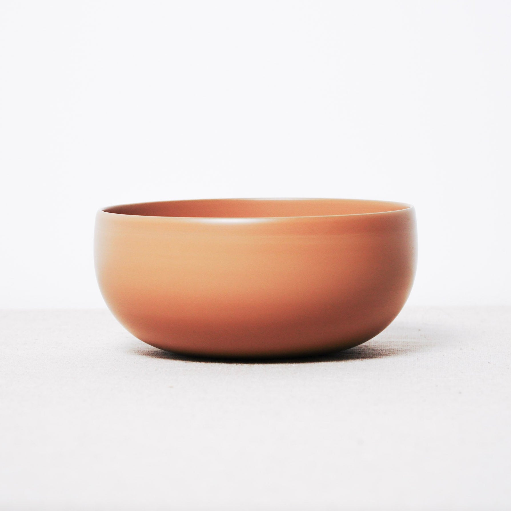 Terracotta-colored ceramic bowl on a white background