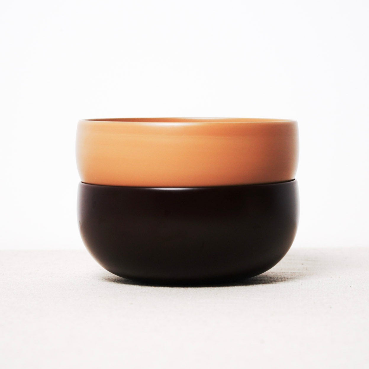Two-toned ceramic bowl with black bottom and brown top on a white background