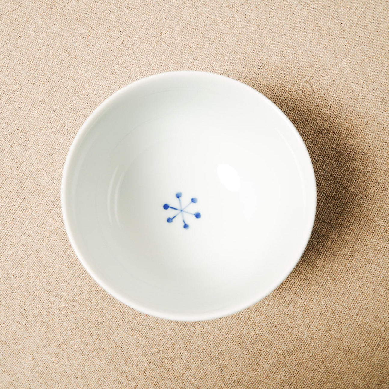 White ceramic bowl with blue design on a beige surface