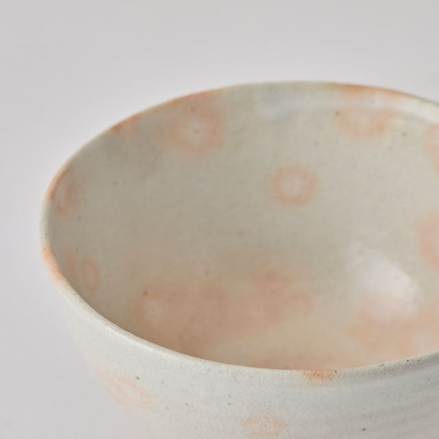 Close-up of a ceramic bowl with speckled pattern on a white background