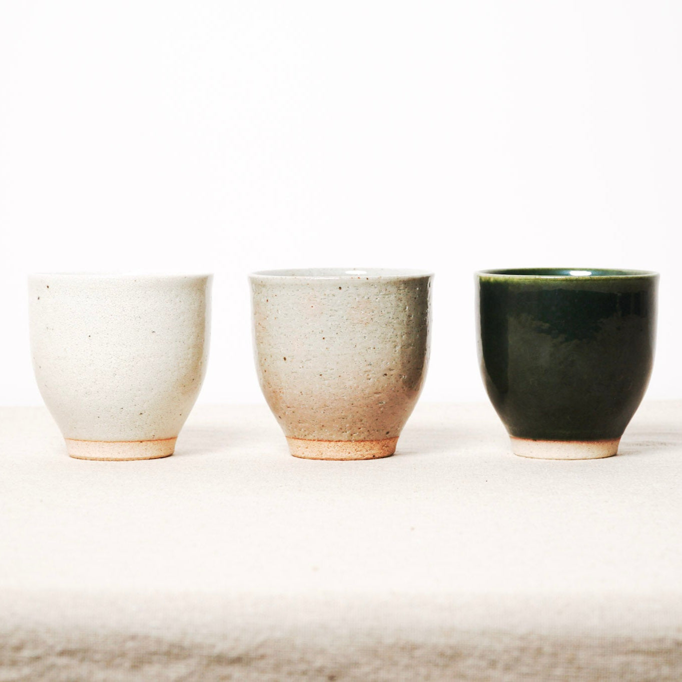 Three ceramic cups of different colors on a white background