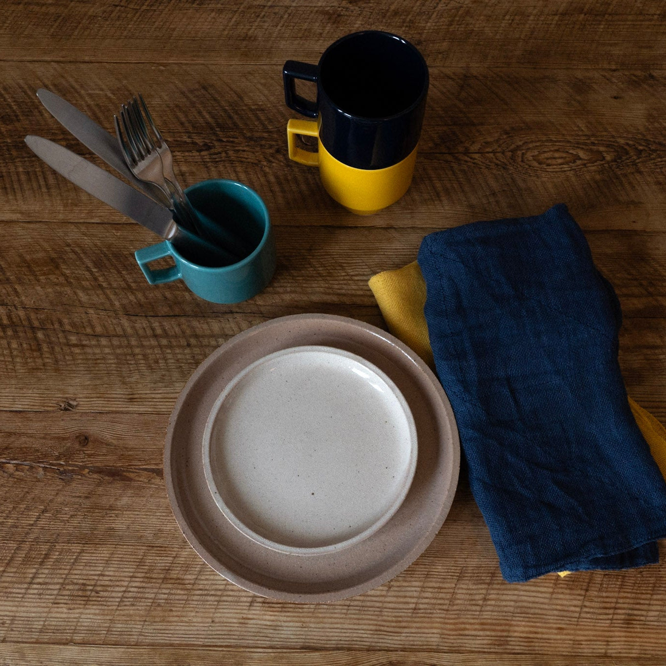 Dishes including a plate, cups, and a towel on a wooden surface