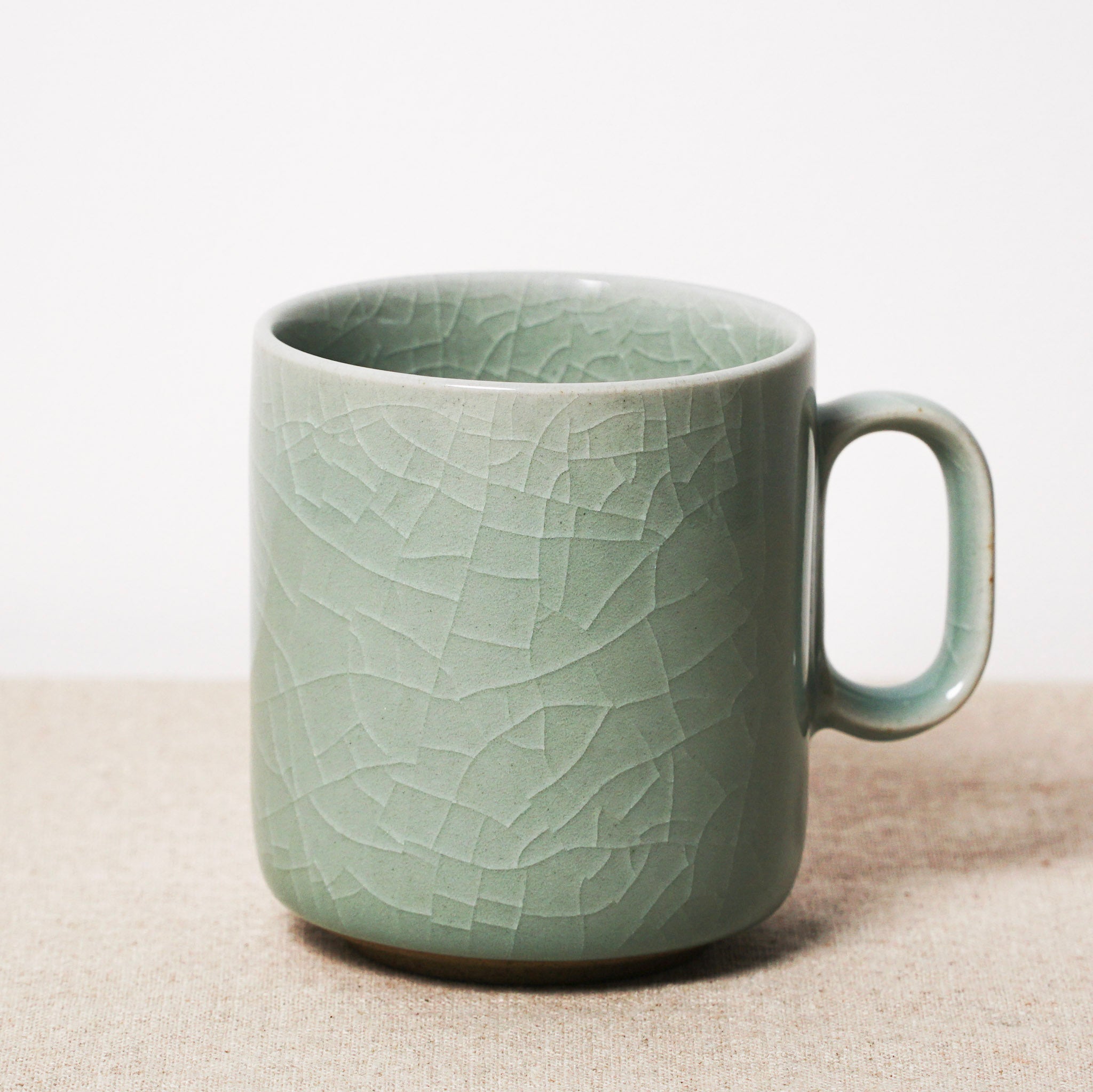 Green ceramic mug with textured surface on a beige surface