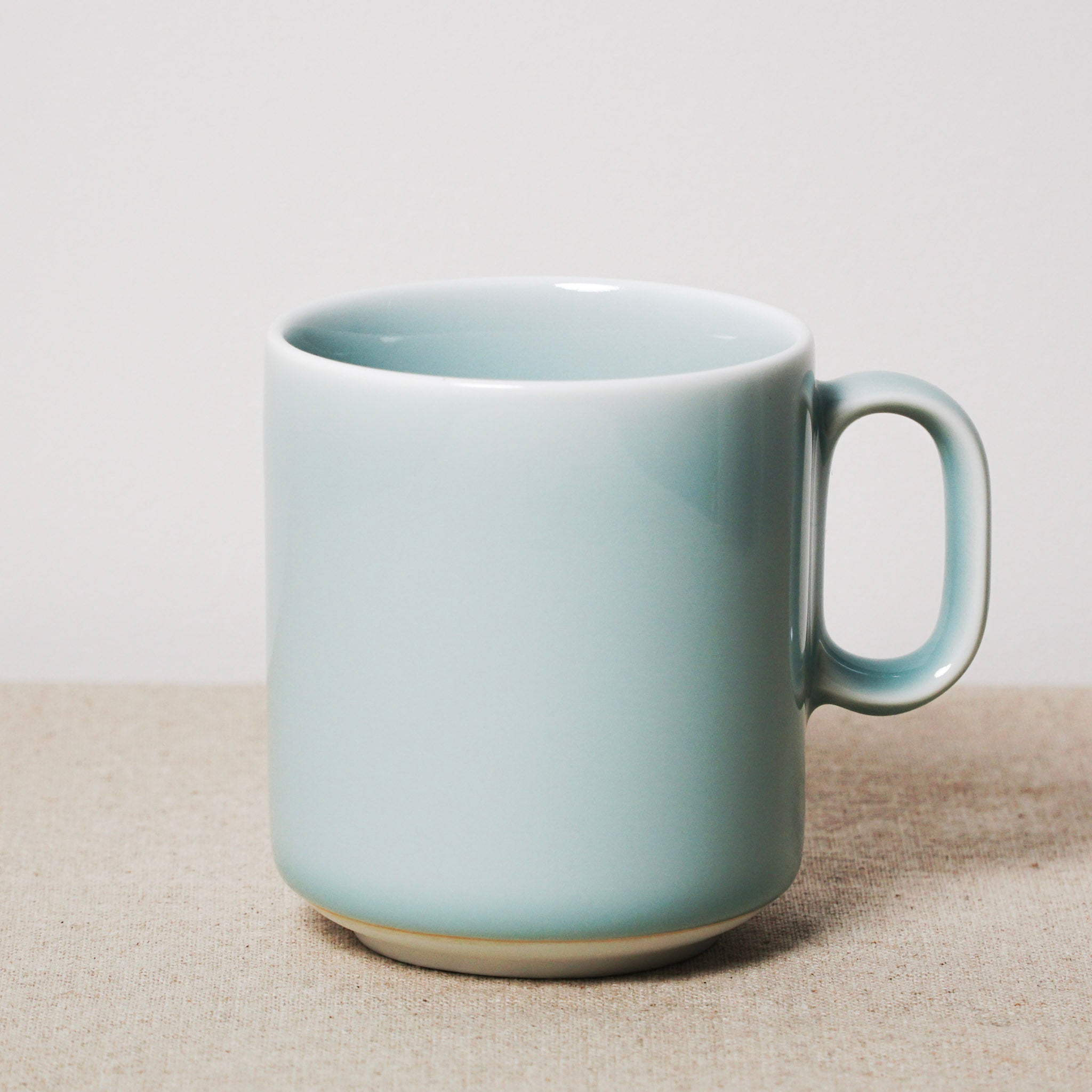 Light blue ceramic mug on a beige surface with a light gray background