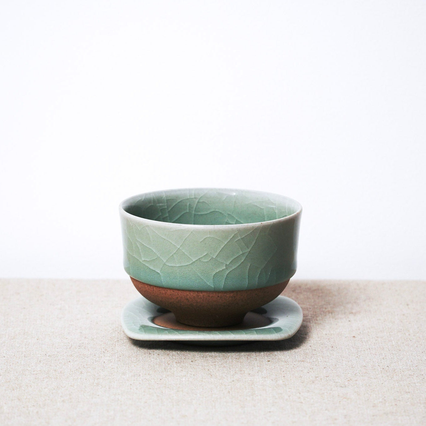 Green ceramic cup with textured design on a matching saucer against a white background