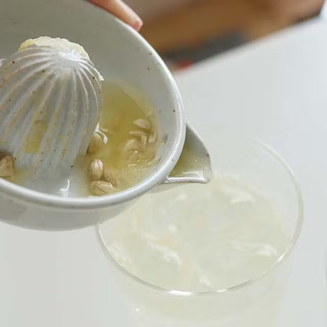 Scallops being added to a bowl of liquid on a white surface