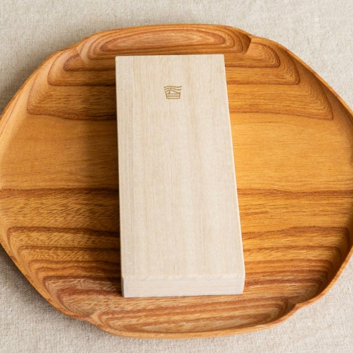 Wooden coaster with a white square object on a textured surface