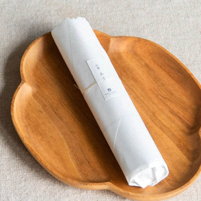 Wooden dish with a white cylindrical object on a light gray background
